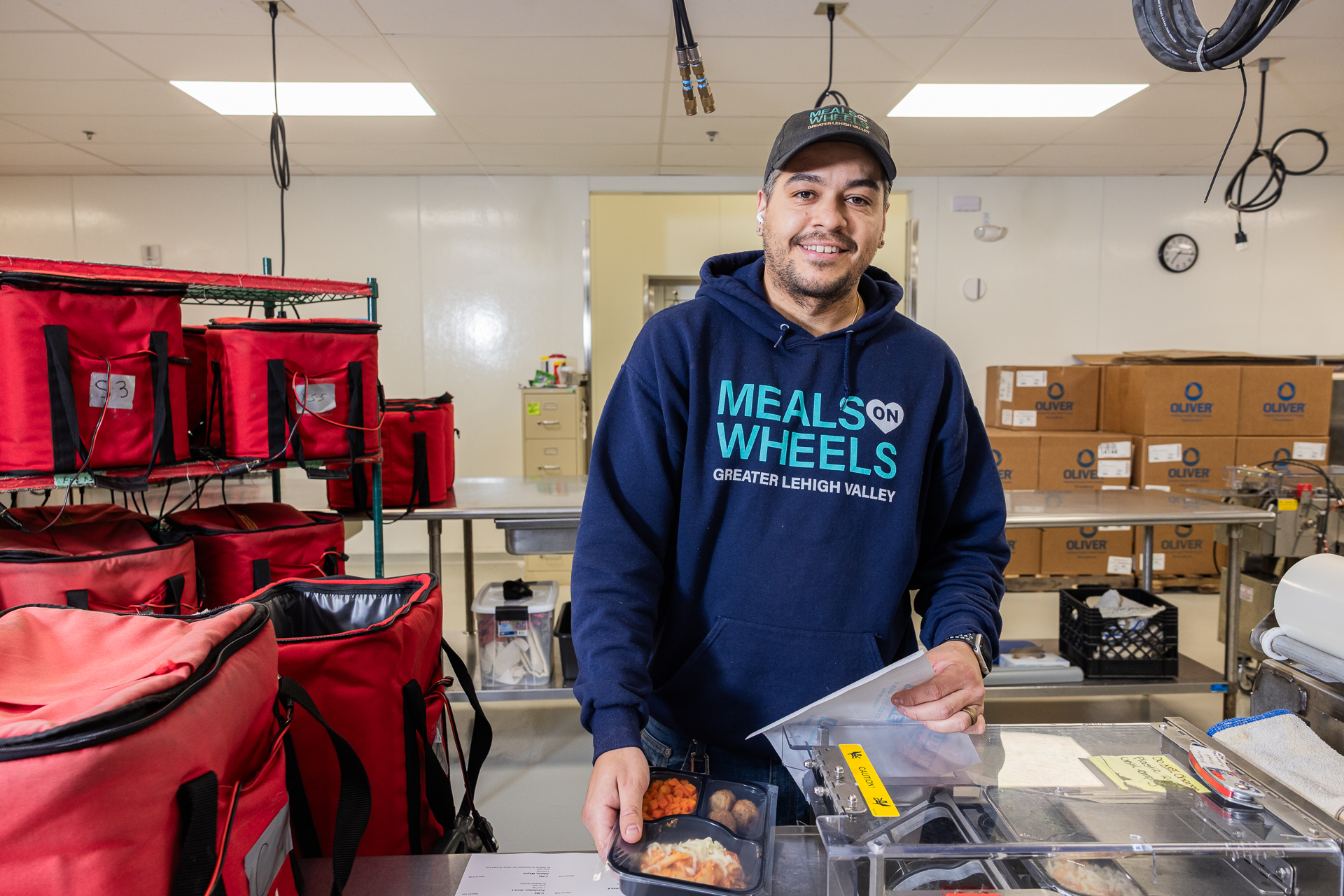 worker wearing Meals on Wheels of the Greater Lehigh Valley sweatshirt packaging food